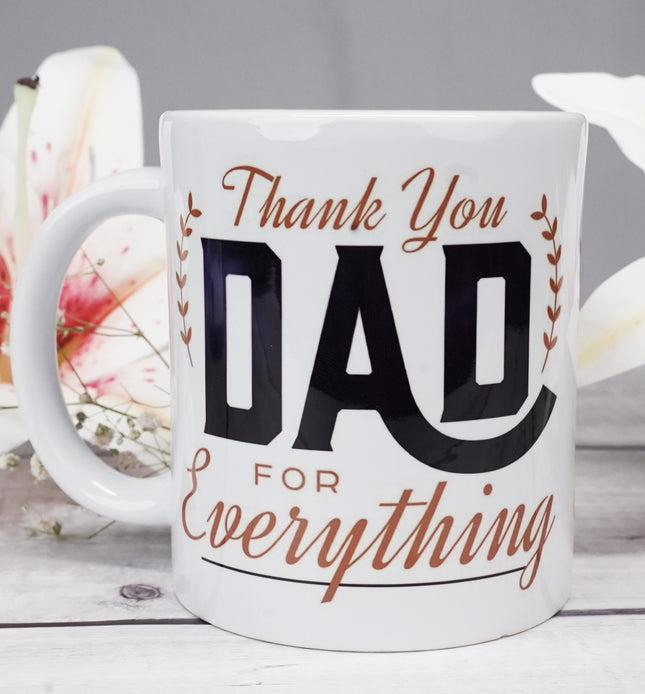 White coffee mug with 'Thank You Dad For Everything' text, wood table, flowers background