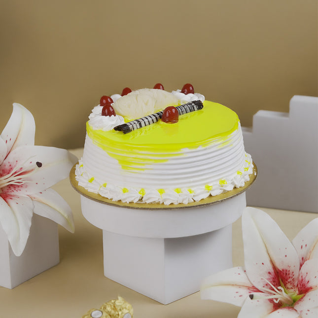 Yellow pineapple cake with cherries and chocolate sticks, decorated with lilies on a beige background