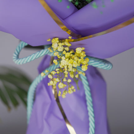 Yellow baby's breath flowers tied with blue rope on a purple bouquet wrapping