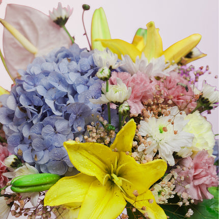 Colorful flower bouquet with yellow lilies, blue hydrangeas, pink carnations, and white daisies