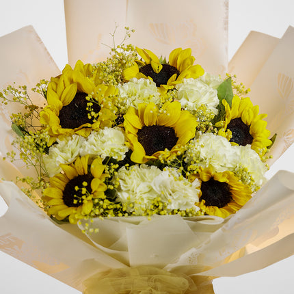 Bouquet of fresh sunflowers and white carnations wrapped in cream floral paper