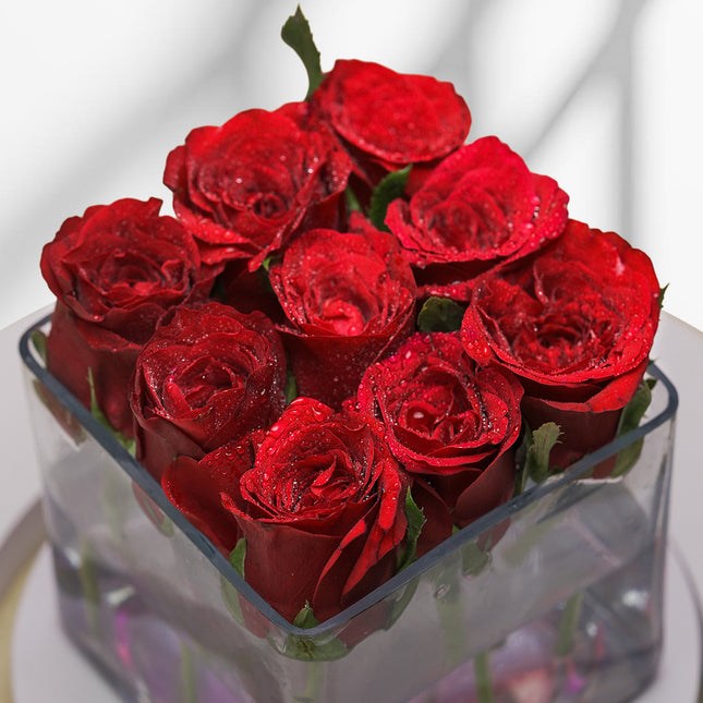 Red roses with water droplets in a glass box, floral arrangement on white background