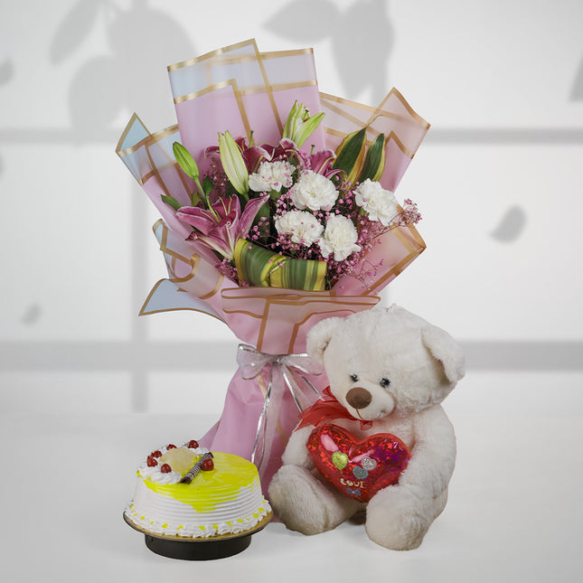 Bouquet of lilies and carnations with a teddy bear and lemon cake on white background